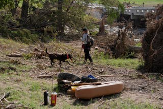 A rescue crew member searches for missing people with a dog in Kerr County. At least 120 people have died and more than 170 are missing